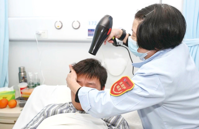 护理员为患者洗头、吹发