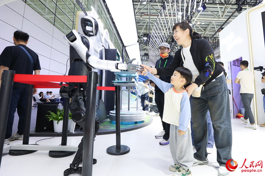 第八届数字中国建设峰会上，小朋友和机器人互动握手。人民网记者 陈永整摄