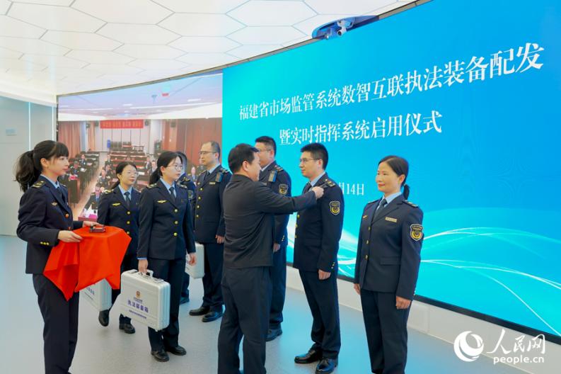 黄水木为执法单位代表发放执法装备。人民网 杨灏昱摄