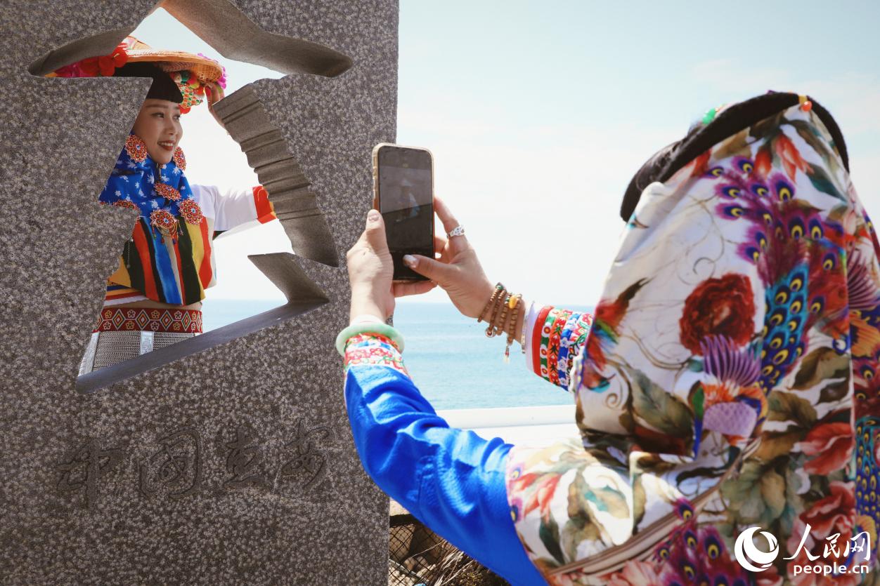 游客身着惠女服饰在海边“打卡”。人民网 李唯一摄